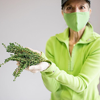 Woman in green holding fresh thyme